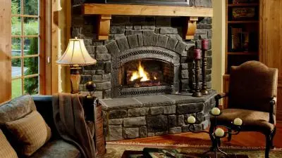 A cozy living room features a stone fireplace, warm lighting, and inviting furniture.