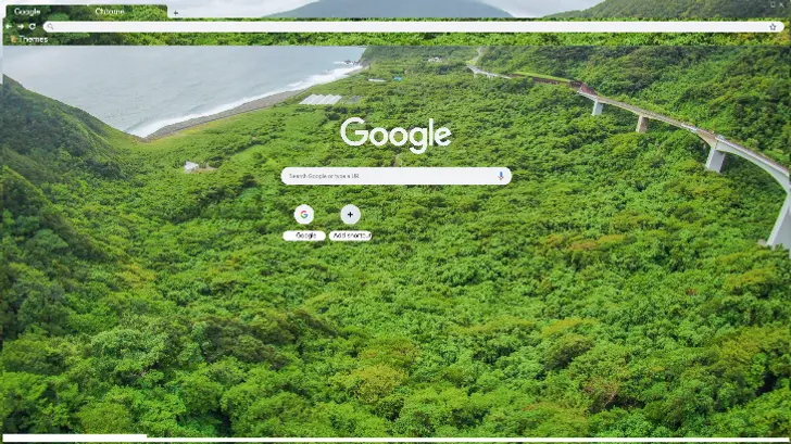 Lush green hillsides descend to a winding road beside a serene coastal landscape.